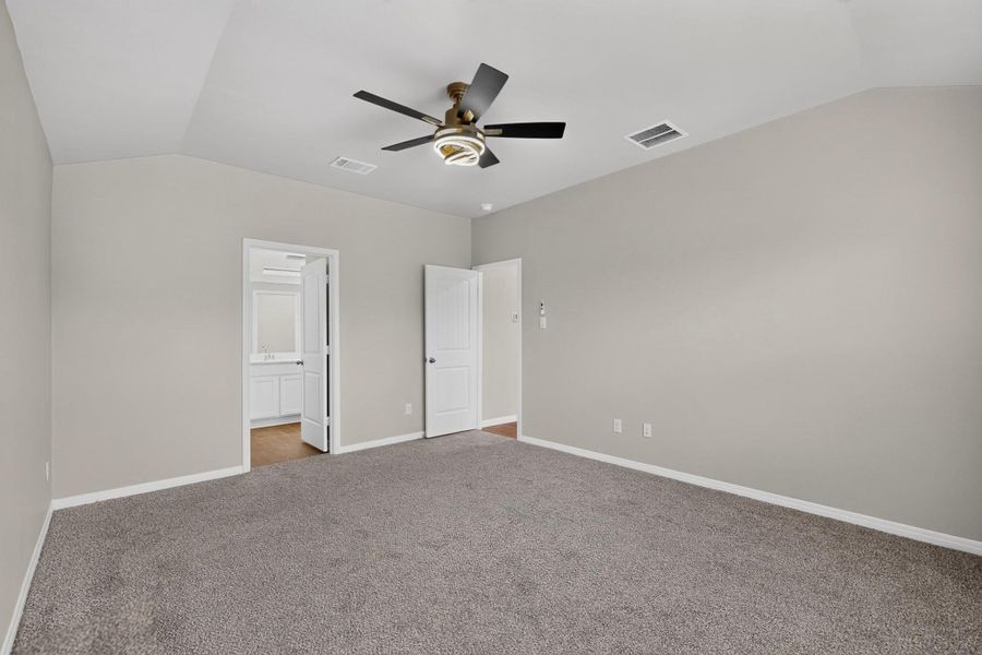 Vaulted ceilings soar above this carpeted bedroom complete with an attached private bath.