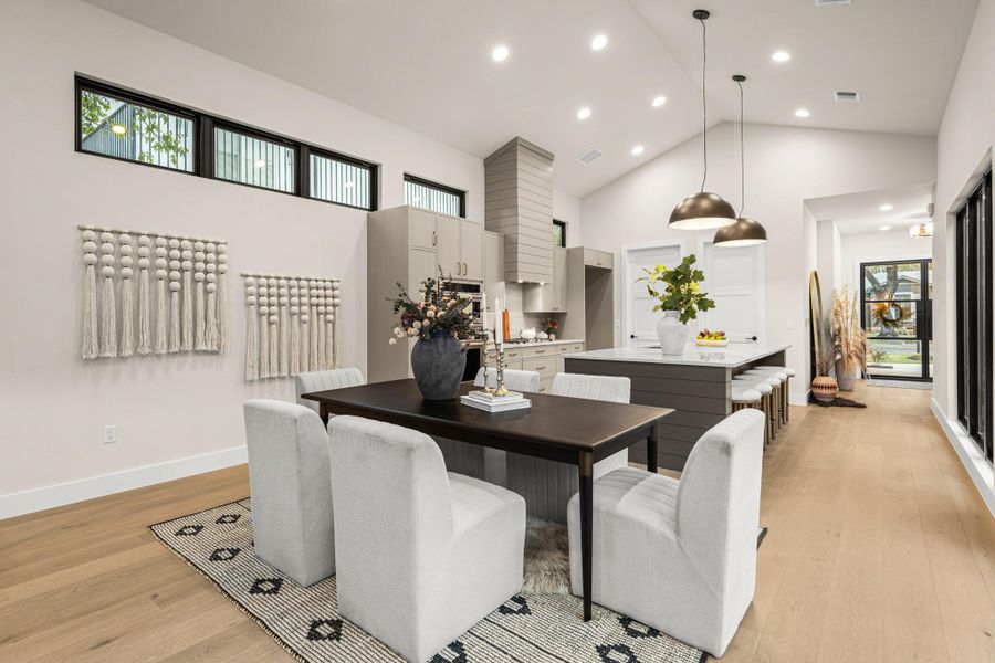 Dining space featuring high vaulted ceiling, light wood-style flooring, and recessed lighting