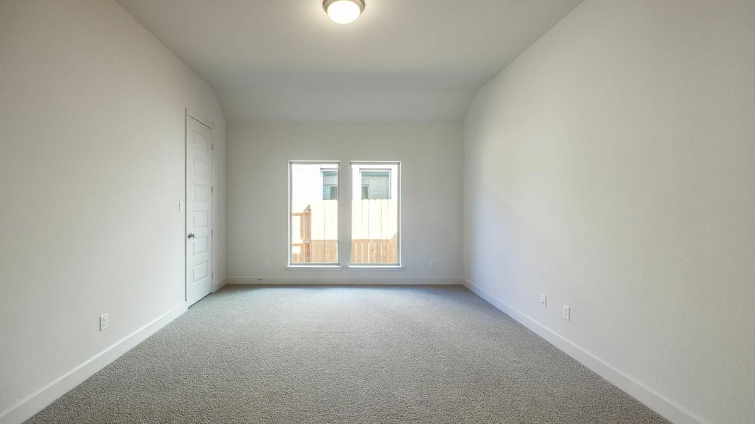 Empty room featuring lofted ceiling, baseboards, and light carpet