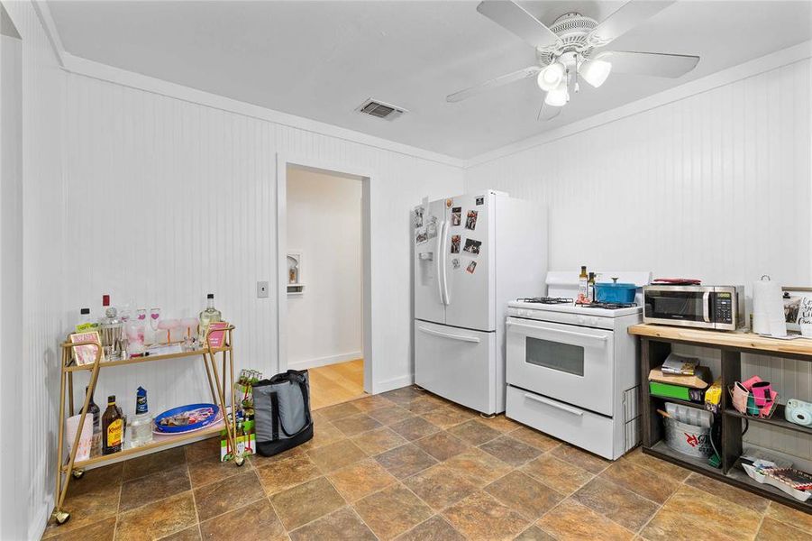 Kitchen with white appliances, stone finish flooring, ornamental molding, and a ceiling fan Kitchen with white appliances, stone finish flooring, ornamental molding, and a ceiling fan