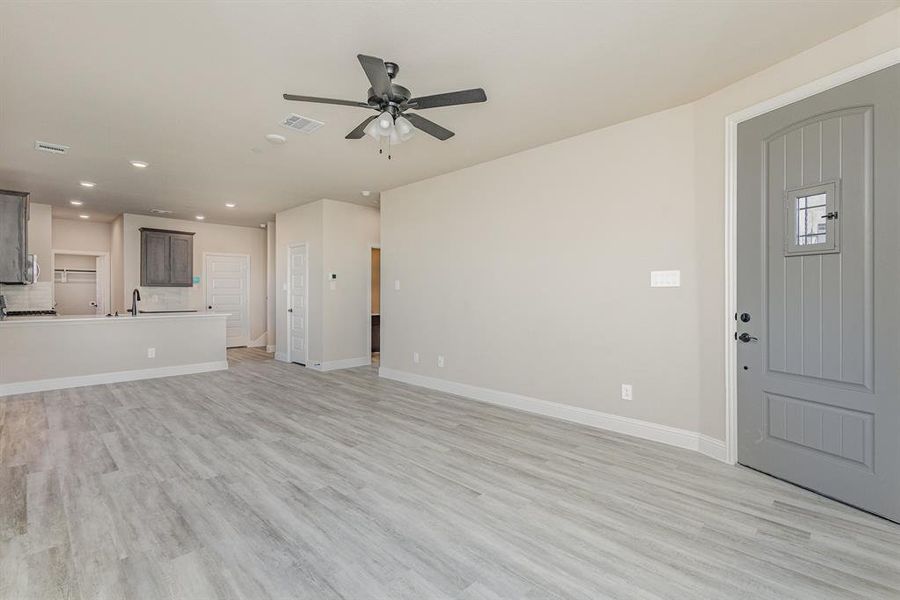 Unfurnished living room with sink, light wood-type flooring, and ceiling fan