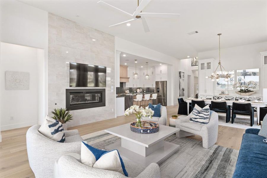 Living area featuring a tile fireplace, a chandelier, light wood-style flooring, a ceiling fan, and recessed lighting Living area featuring a tile fireplace, a chandelier, light wood-style flooring, a ceiling fan, and recessed lighting