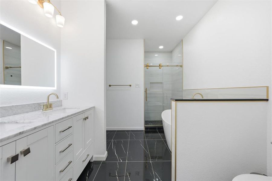 Full bathroom with double vanity, a shower stall, recessed lighting, and a freestanding bath Full bathroom with double vanity, a shower stall, recessed lighting, and a freestanding bath