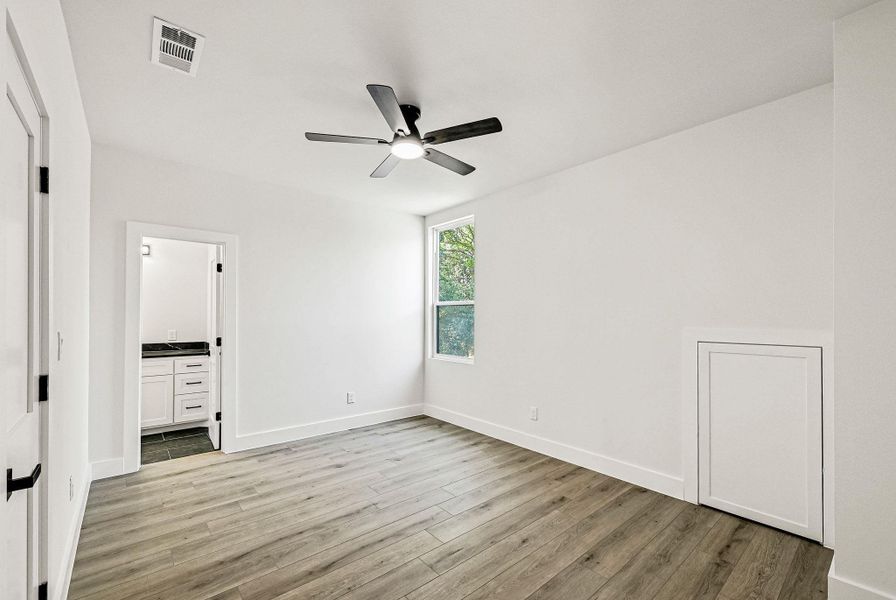 Unfurnished bedroom featuring light wood-style flooring, ceiling fan, and ensuite bath