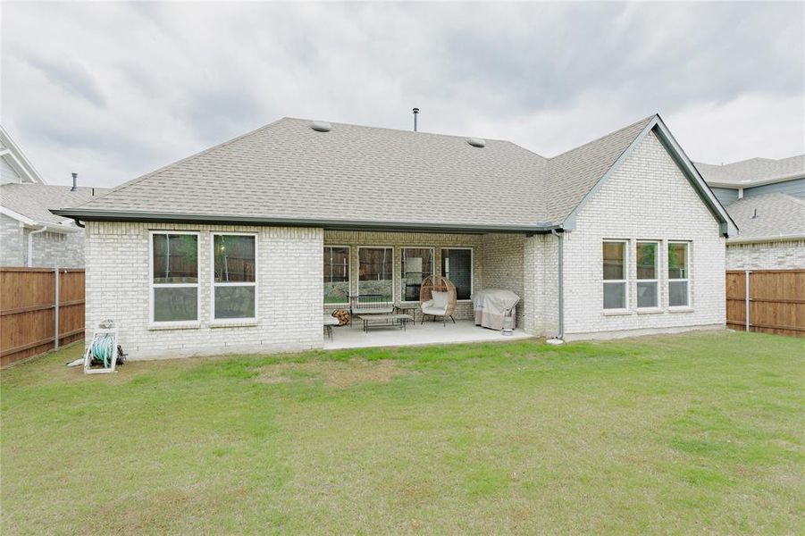 Expansive backyard featuring a manicured lawn, full fencing, and a covered patio
