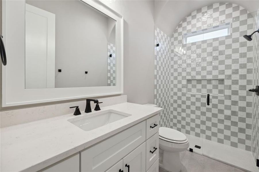 Bathroom with vanity, a shower with shower door, and toilet