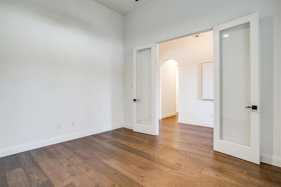 Large study with french doors featuring inlaid glass, ceiling fan and large window