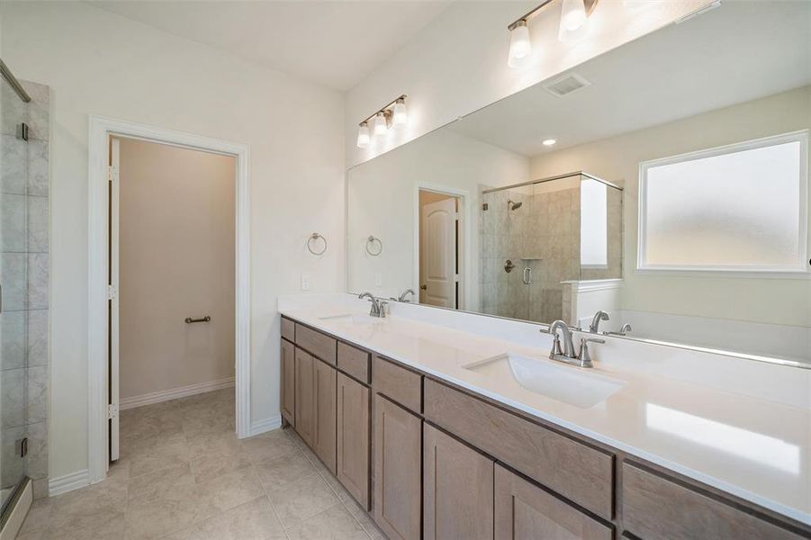 Bathroom featuring a stall shower, double vanity, and light tile patterned floors