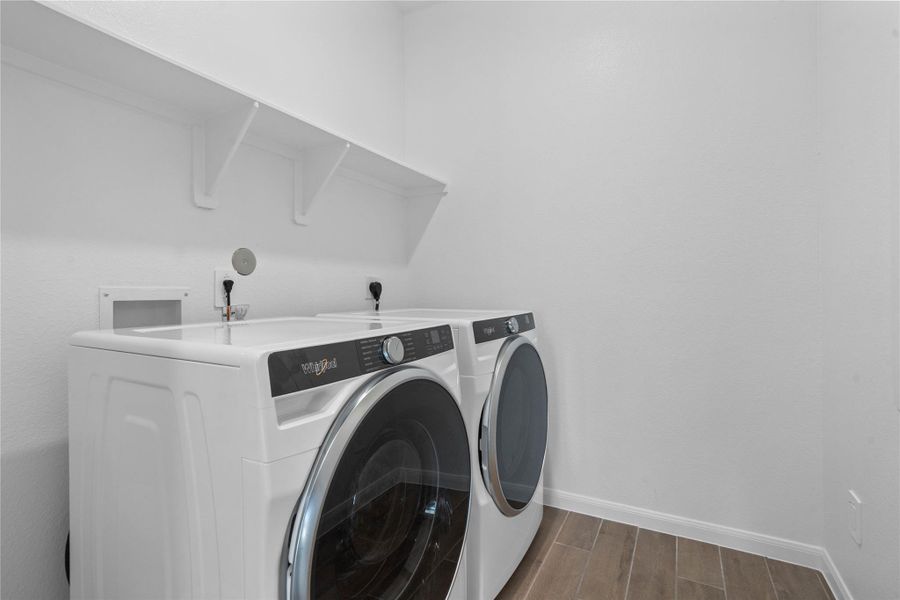 This dedicated laundry room comes equipped with a washer and dryer set, ready for immediate use. This laundry room is conveniently located near the primary bedroom.