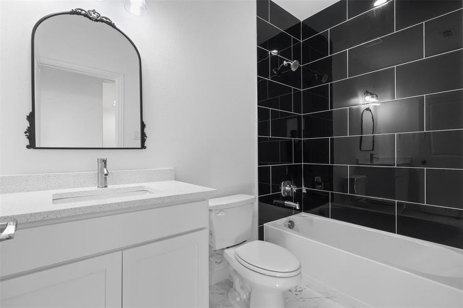 Full bathroom featuring tiled shower / bath combo, toilet, and vanity