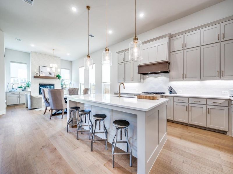 Kitchen featuring gray cabinets, a sink, decorative backsplash, a breakfast bar area, and light wood finished floors