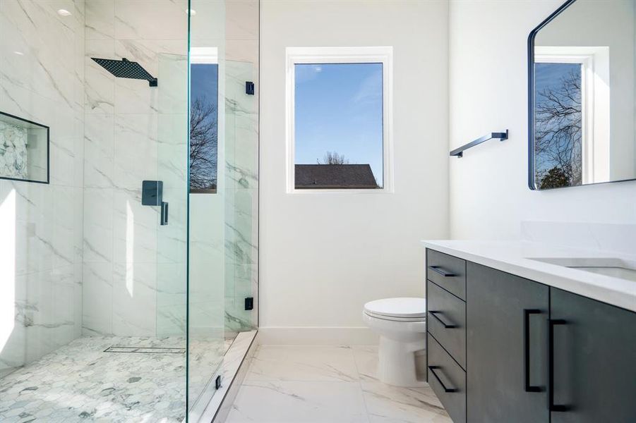 Bathroom with toilet, vanity, and a shower with shower door