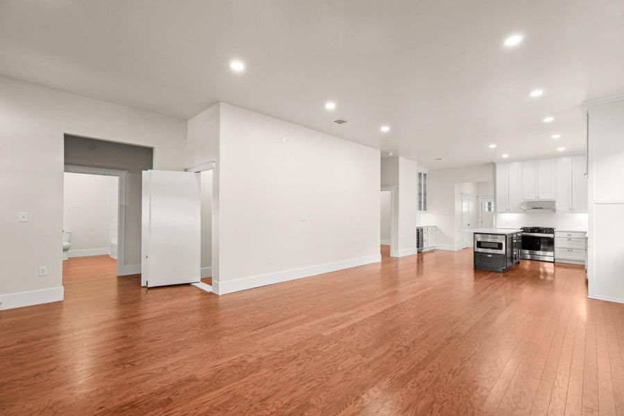 Natural wood floors extend throughout this open-concept living space with a modern kitchen. Natural wood floors extend throughout this open-concept living space with a modern kitchen.