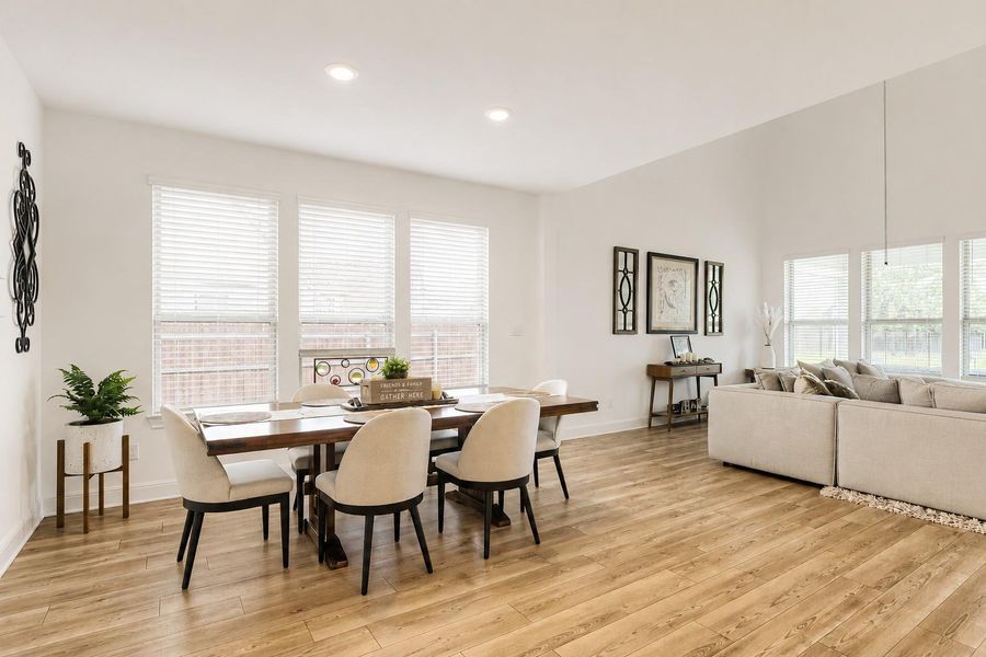 An open-concept living space features warm wood flooring and ample natural light from numerous windows. An open-concept living space features warm wood flooring and ample natural light from numerous windows.