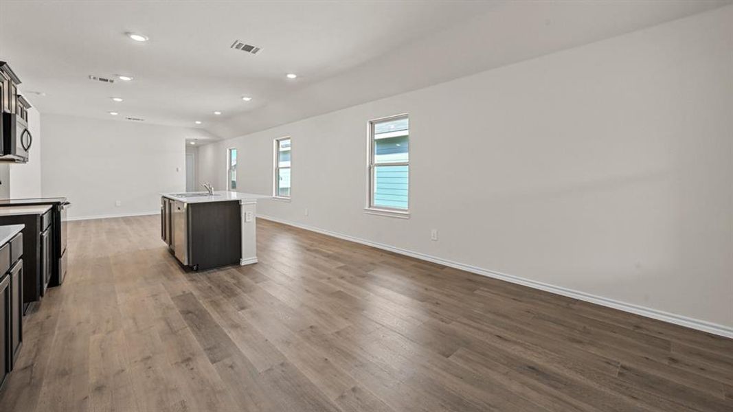 Open-concept living area featuring wood-finish flooring, recessed lighting, and multiple windows with white trim