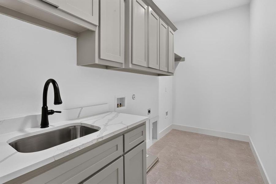 Utility room featuring a built-in sink with a matte black faucet, light gray cabinetry, white countertops with veining, and neutral tile flooring Utility room featuring a built-in sink with a matte black faucet, light gray cabinetry, white countertops with veining, and neutral tile flooring