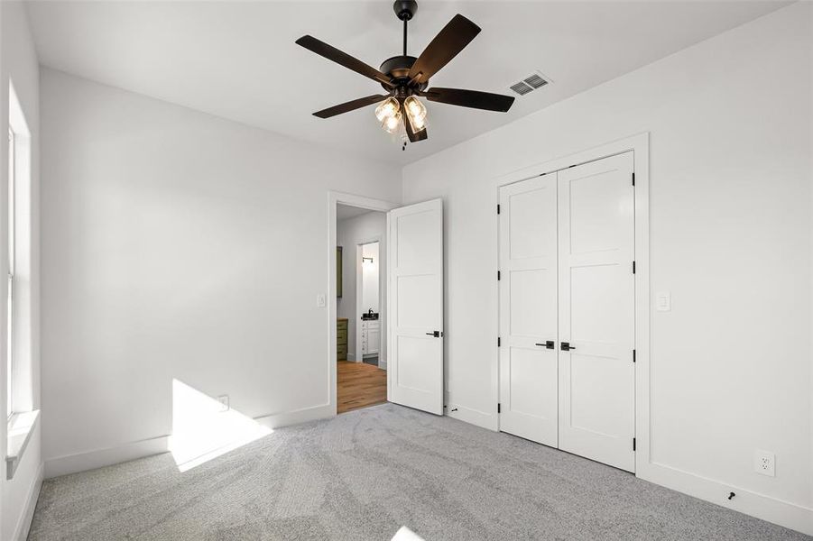 Unfurnished bedroom with ceiling fan, light colored carpet, and a closet