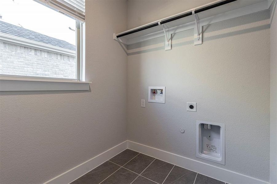 Laundry area featuring dark tile patterned floors, hookup for a washing machine, hookup for a gas dryer, electric dryer hookup, and a textured wall