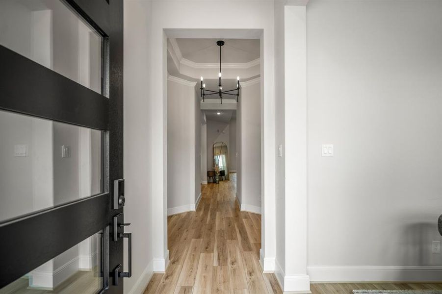 Walking in, you find a bright entryway with beautiful light wood like flooring that continues into the main living areas making it easy to clean and maintain. You'll love the dtailed entrance featuring crown molding, trace ceiling, modern chandelier, and rotunda.