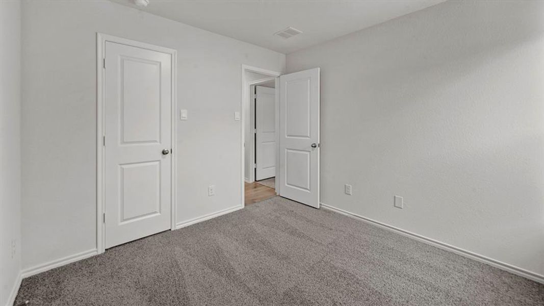 Spacious room featuring neutral paint, gray carpeting, a two-panel interior door, and white baseboards