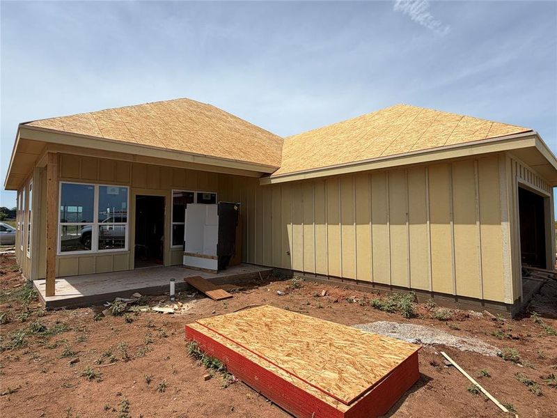 Newly constructed residence featuring board and batten style siding and a covered patio