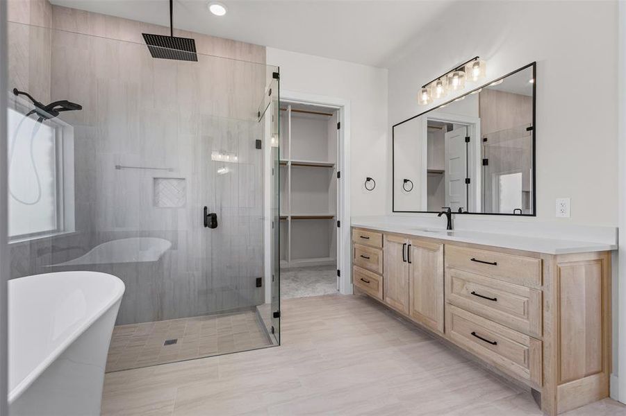 Bathroom featuring a shower stall, vanity, a freestanding bath, a walk in closet, and recessed lighting