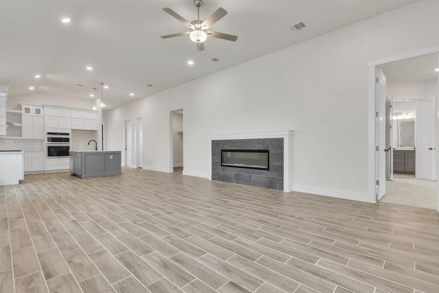 An open-concept living space integrates a contemporary fireplace and a modern kitchen with a central island.