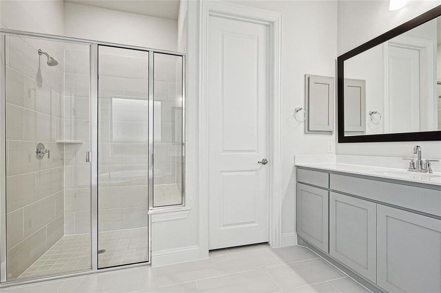 Bathroom with vanity, a shower with shower door, and tile patterned floors