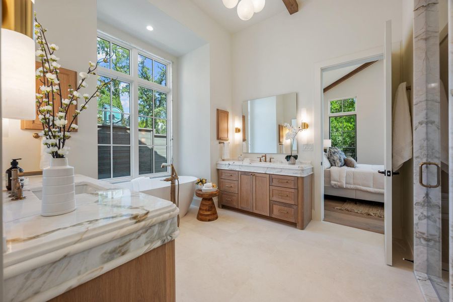 Fine stone countertops and a freestanding tub define this elegant primary bathroom.