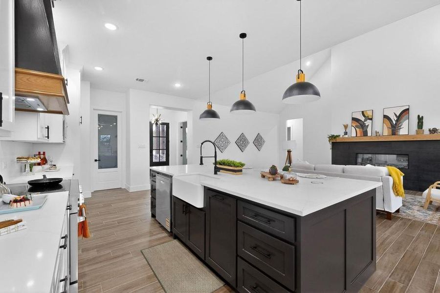Kitchen featuring hanging light fixtures, appliances with stainless steel finishes, light stone counters, wood finish floors, and vaulted ceiling Kitchen featuring hanging light fixtures, appliances with stainless steel finishes, light stone counters, wood finish floors, and vaulted ceiling