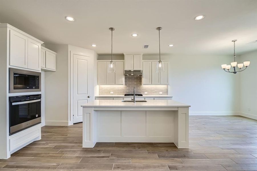 Kitchen featuring oven, a sink, tasteful backsplash, light countertops, and built in microwave