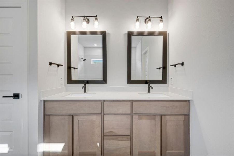 Dual vanity featuring light wood-finish cabinetry, white countertops, and matte black fixtures