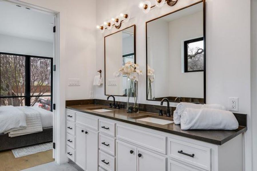 Ensuite bathroom with double vanity, connected bathroom, and a sink