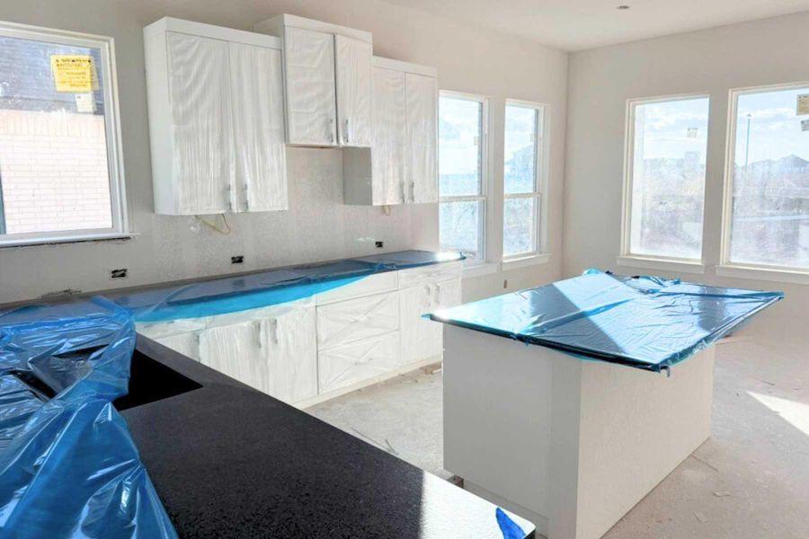 Kitchen with white cabinetry, a center island, and backsplash Kitchen with white cabinetry, a center island, and backsplash
