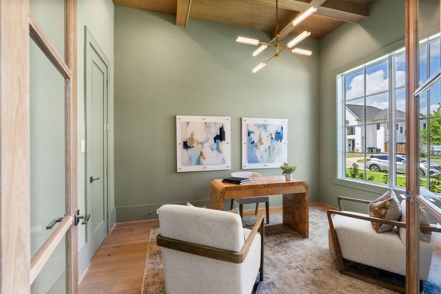 Just off the entry, a private home office is framed by custom white oak doors and elevated by soaring ceilings. Natural light pours in through large windows, highlighting the refined finishes and craftsmanship.