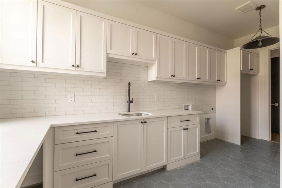 Kitchen featuring decorative backsplash, white cabinets, pendant lighting, and dark tile patterned flooring Kitchen featuring decorative backsplash, white cabinets, pendant lighting, and dark tile patterned flooring