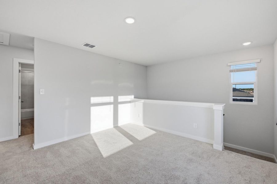 An open and versatile loft space with soft carpet, naturally illuminated by a single window, offers flexible living arrangements.