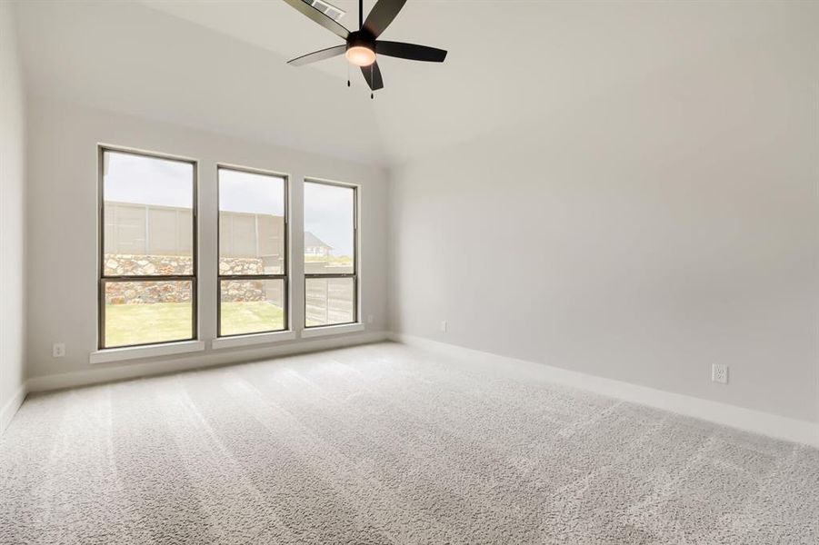 Spacious main bedroom room featuring vaulted ceilings, a contemporary ceiling fan, and light-toned carpet flooring