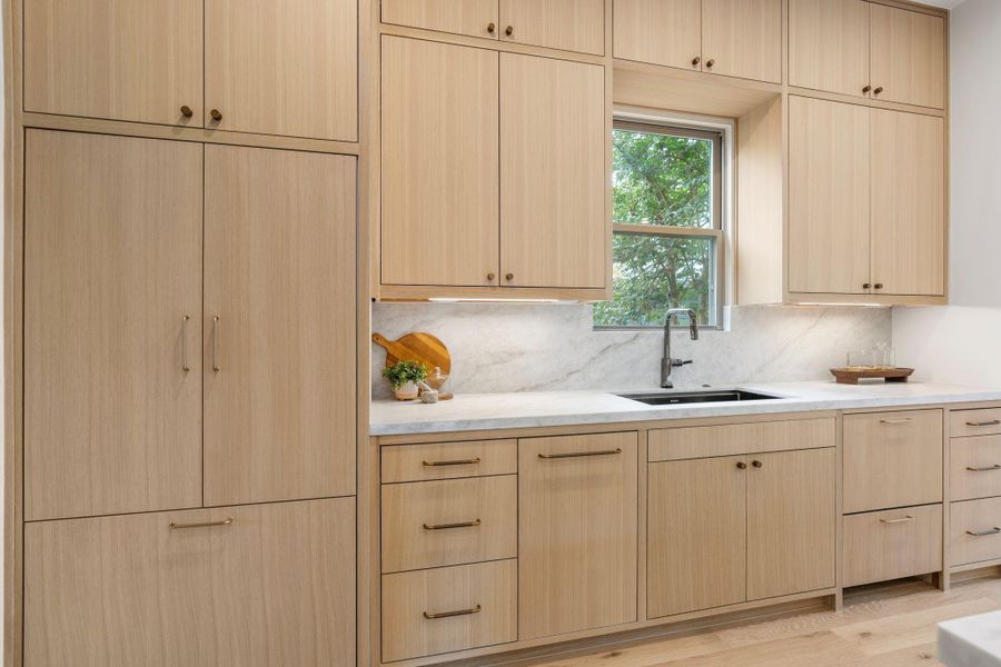 A panel-integrated Fisher & Paykel refrigerator and double-drawer dishwasher, seamlessly clad in white oak and accented with designer hardware. A panel-integrated Fisher & Paykel refrigerator and double-drawer dishwasher, seamlessly clad in white oak and accented with designer hardware.