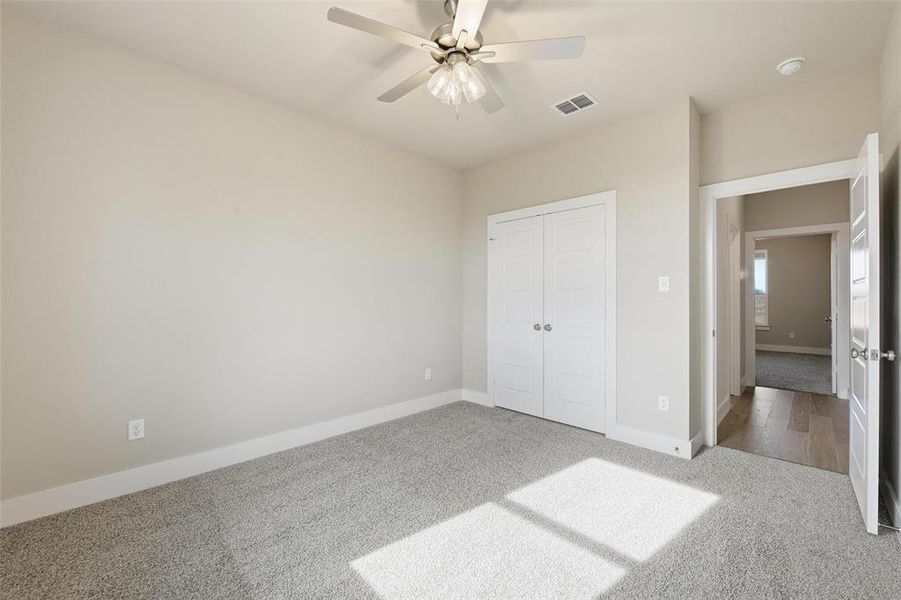 Unfurnished bedroom with light colored carpet, ceiling fan, and a closet