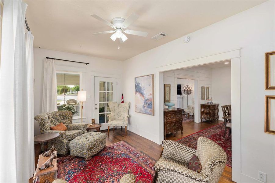 Bright living space featuring wood-finish flooring, a ceiling fan, and white trim throughout