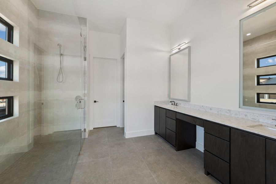 Full bathroom featuring double vanity, a stall shower, and light tile patterned floors