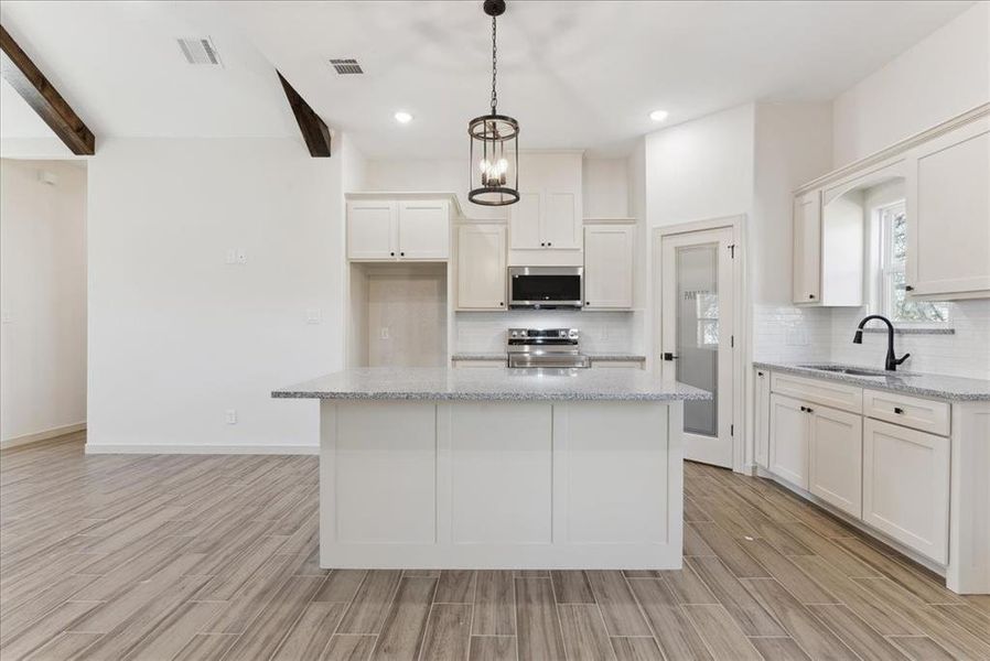 Kitchen featuring white cabinetry, a kitchen island, and stainless steel appliances