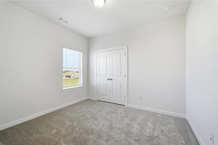 Carpeted room with a double-door closet, a single window, and a flush mount ceiling light fixture