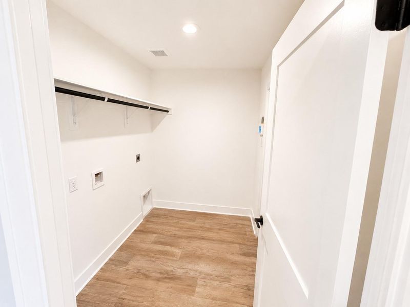 Utility room featuring modern finishes, wood-look flooring, built-in shelving, and ample space for storage and everyday convenience.