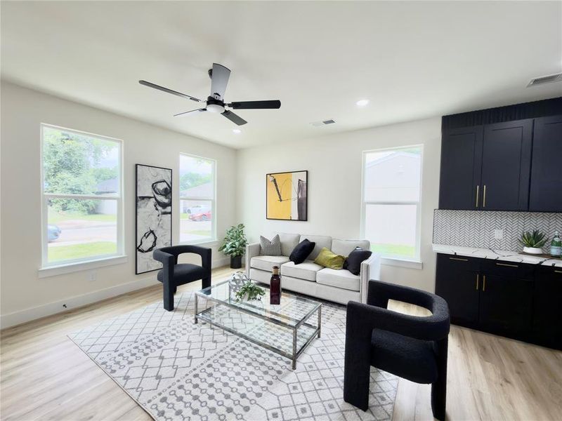 Bright living area featuring wood-finish flooring, white walls, and a contemporary ceiling fan