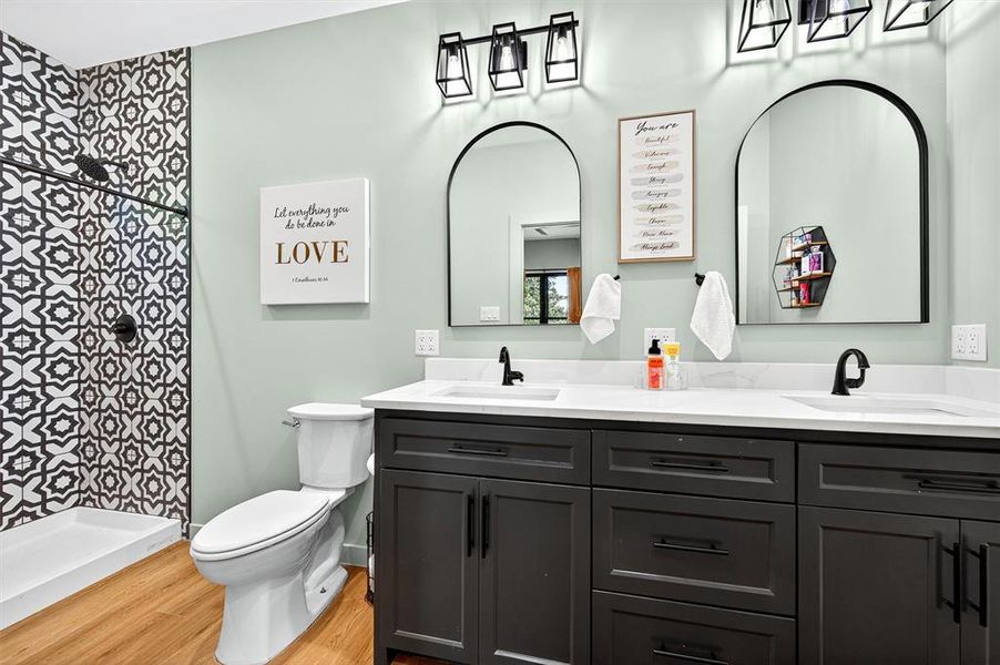 Full bath featuring double vanity, light wood finished floors, and tiled shower Full bath featuring double vanity, light wood finished floors, and tiled shower