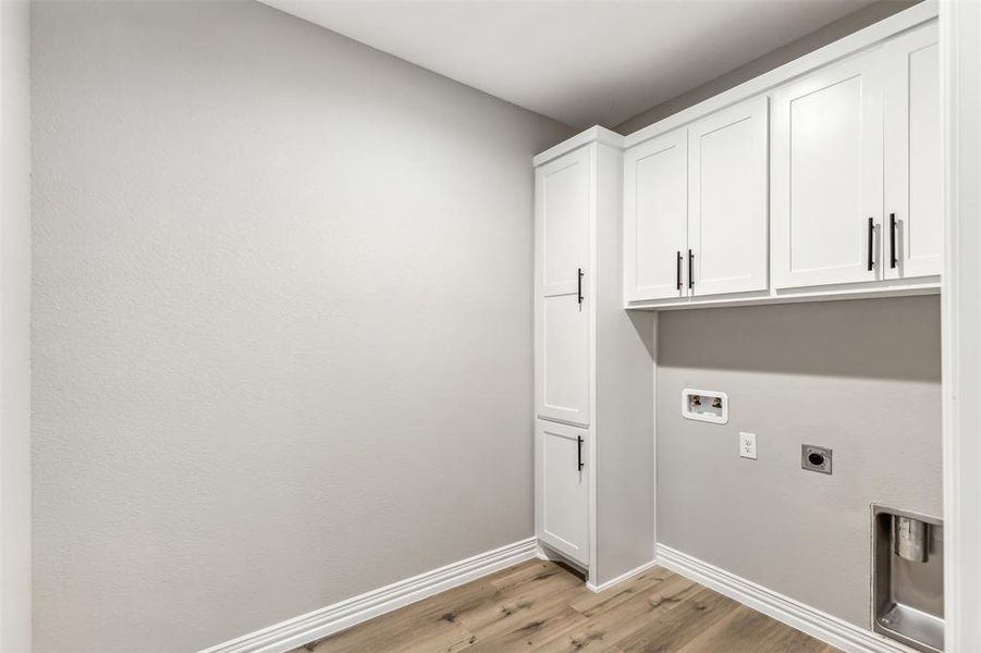 Washroom with light wood-type flooring, cabinets, washer hookup, and electric dryer hookup