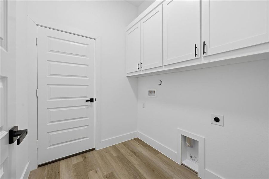 Laundry area featuring light wood-style flooring, cabinet space, hookup for a washing machine, and electric dryer hookup
