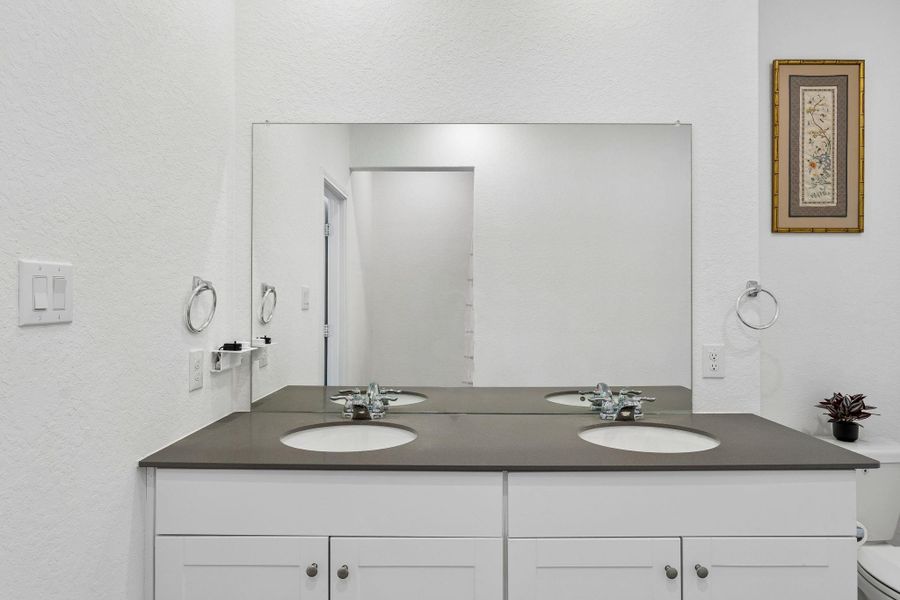 Primary bathroom with double vanity with sleek countertops offers practical elegance in this well-appointed bathroom.